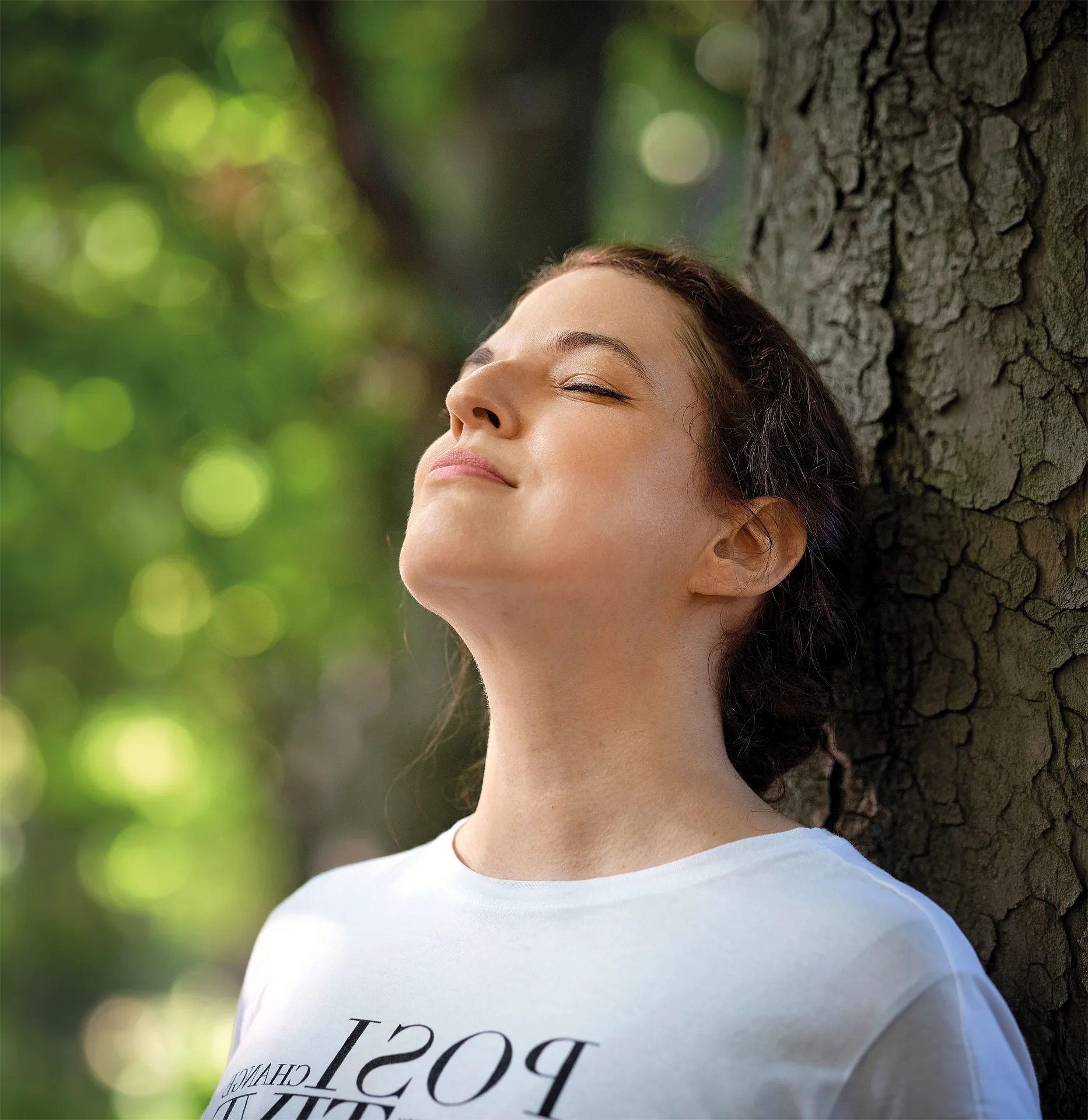 Mentaltrainerin Katharina Riedl lehnt sich entspannt mit geschlossenen Augen an einem Baum